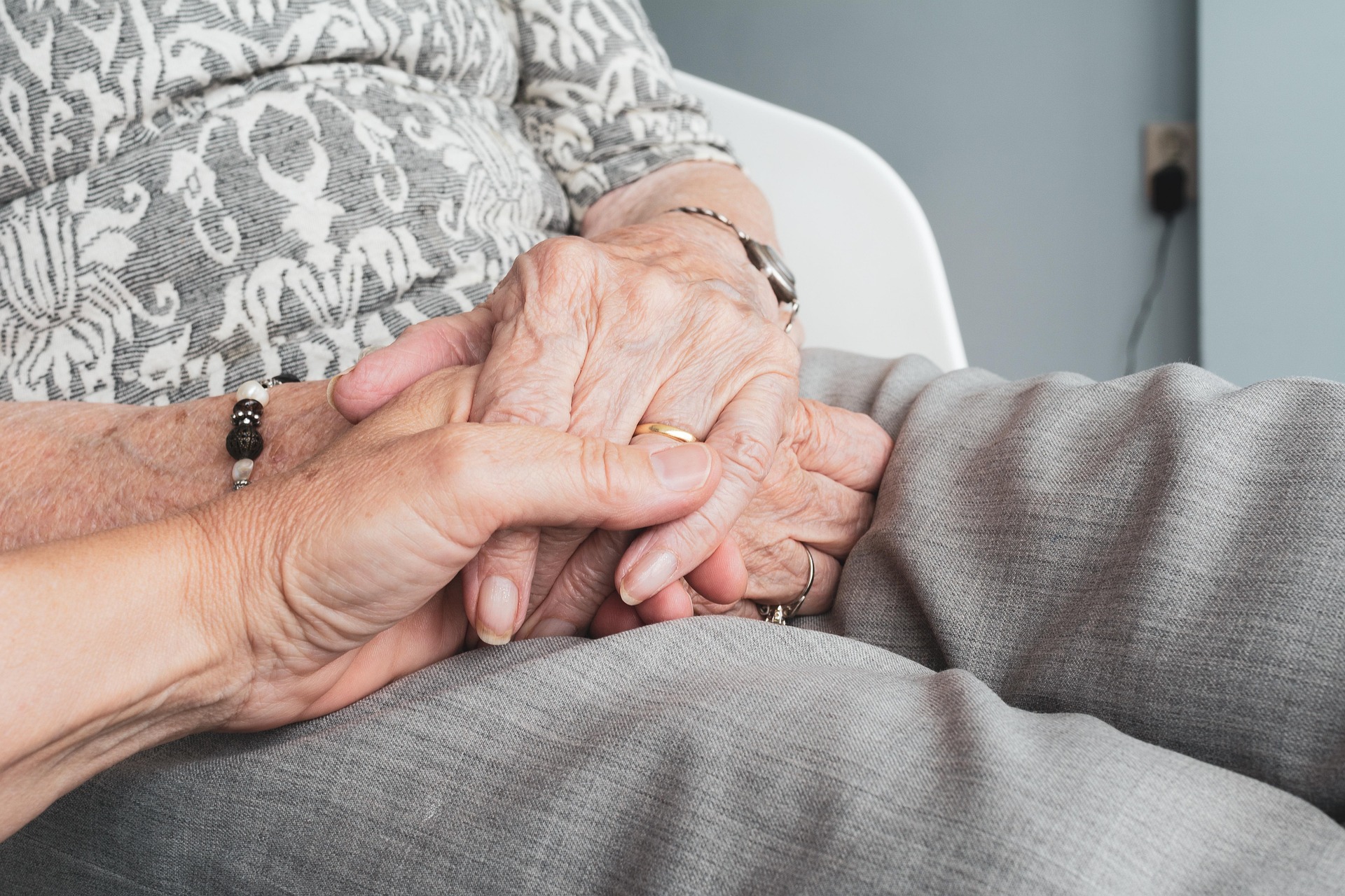 A caregiver gently holding a patient's hands